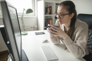 Young woman working from home looking at computer screen